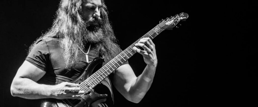 John Petrucci performs on stage with his 7-string guitar, showcasing his virtuosity with Dream Theater.