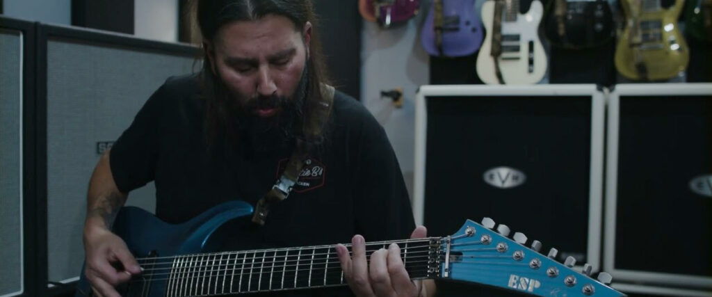 Stephen Carpenter of Deftones deeply engrossed in playing his 7-string guitar, demonstrating his signature heavy metal style.