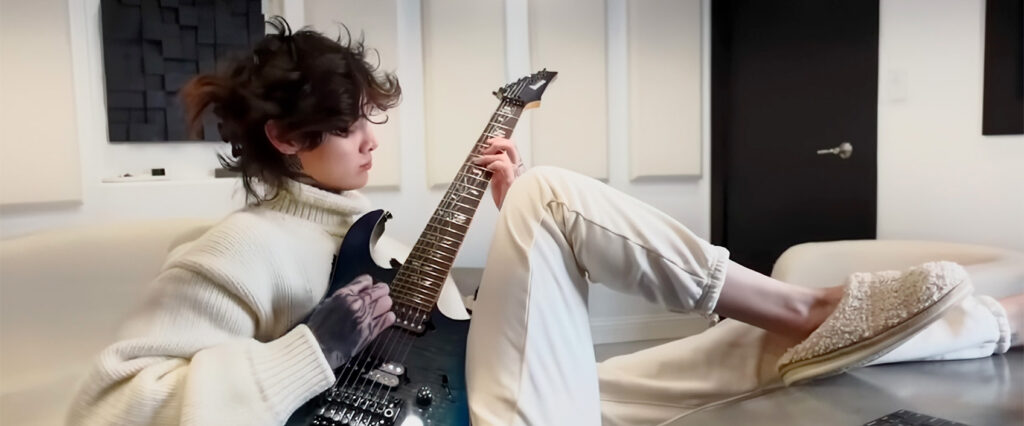 Tim Henson, lead guitarist of Polyphia, playing a 7-string guitar with a focus and intensity that matches his musical prowess.