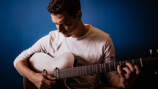 Alex Jung playing guitar, showcasing his musical talent in a live performance